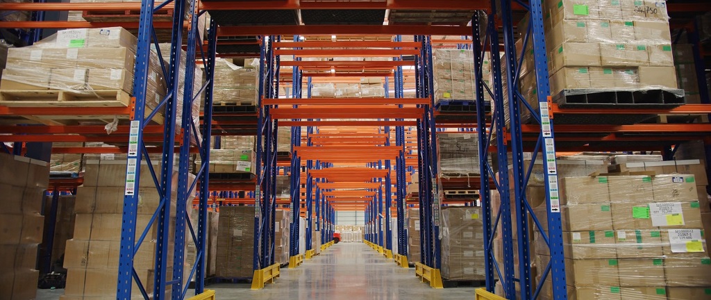 Large warehouse with tall shelves stacked with pallets and boxes ready for distribution